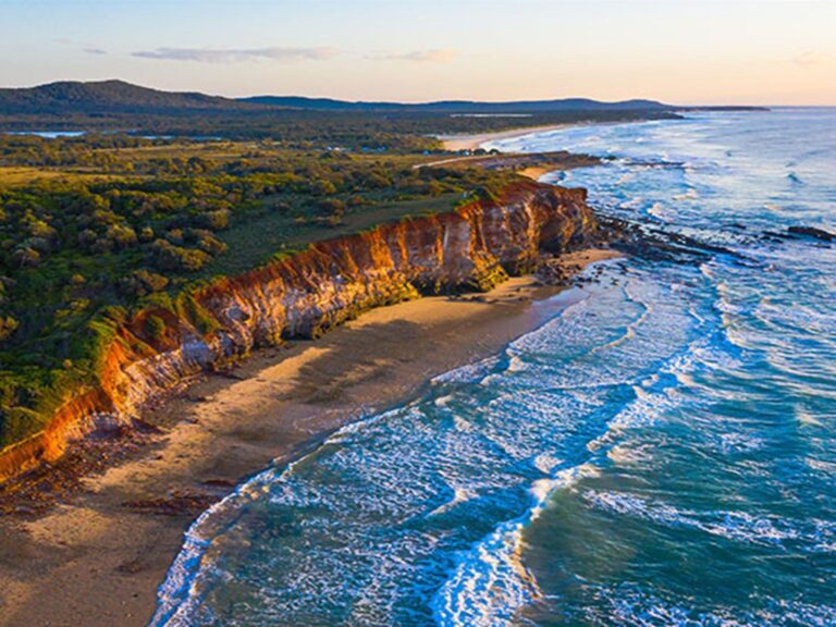 Aerial shot of the red cliffs at Lake Arragan and Red Cliff campgrounds in Yuraygir National Park.
